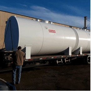 Man standing in front of cylindrical tank